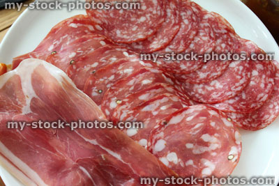 Stock image of cold meat platter, white plate, Italian prosciutto ham, salami slices