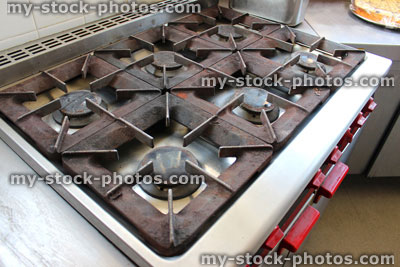 Stock image of dirty, rusty gas cooker hob in commercial kitchen