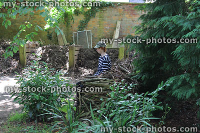 Stock image of teenage gardener boy taking rest in garden, sitting by compost heaps