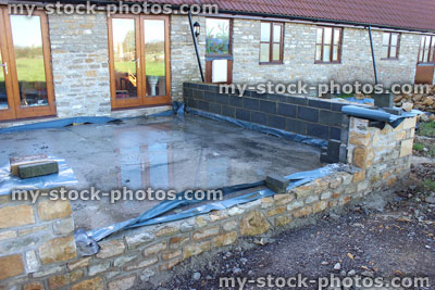 Stock image of conservatory foundations / stone wall being built behind bungalow barn conversion