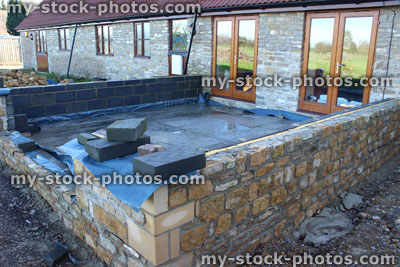 Stock image of conservatory foundations / stone wall being built behind bungalow barn conversion