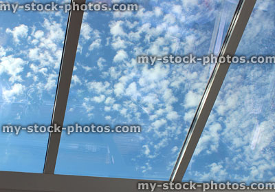 Stock image of glass conservatory roof large tinted window panels, sunny blue sky
