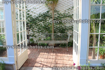 Stock image of white metal conservatory seat / bench, block paving, summerhouse