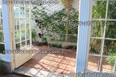 Stock image of white metal conservatory seat / bench, block paving, ponytail palm / beaucarnea recurvata