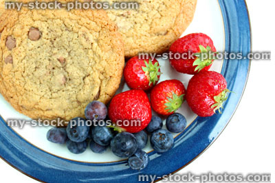 Stock image of homemade chocolate chip cookies, with strawberries and blueberries