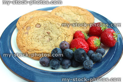 Stock image of homemade chocolate chip cookies, with strawberries and blueberries