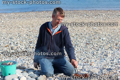 Stock image of man cooking food on charcoal barbecues at beach