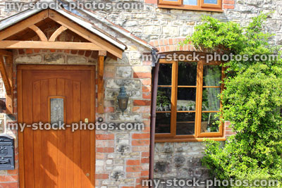 Stock image of wooden front door on stone cottage, with triangular porch roof