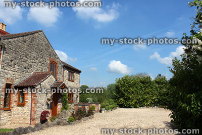 Stock image of historic stone cottage in England, gardens, blue sky