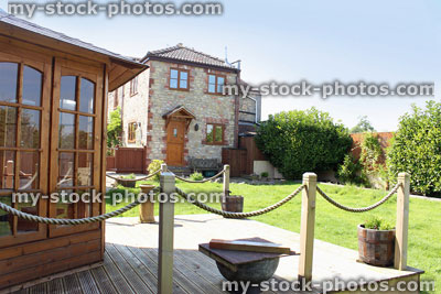 Stock image of back garden, with stone cottage, decking, wooden gazebo
