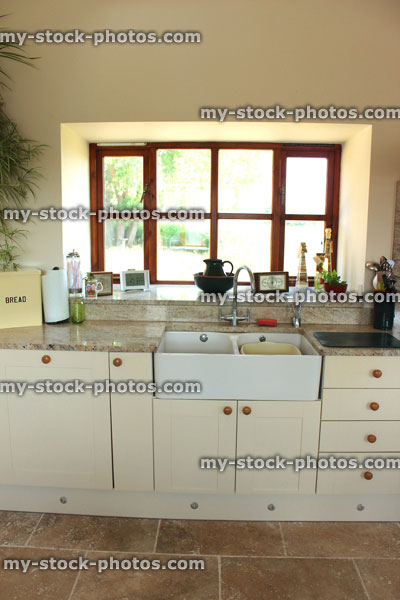 Stock image of country kitchen, cream Shaker cabinet doors, double Belfast sink, drawers