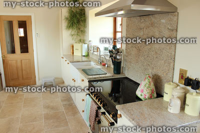 Stock image of shaker style country kitchen with granite worktop surface, gas range cooker