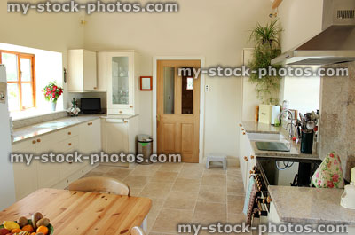 Stock image of country kitchen, granite worktop, gas range cooker, tiled floor, pine table