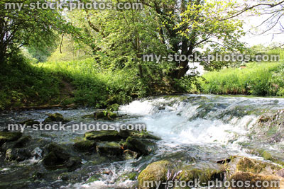 Stock image of healthy fast flowing river with clear water travelling over a weir