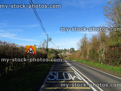 Stock image of bendy, winding road sign triangle, white slow painted on road, yellow lines