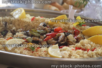 Stock image of vegetarian couscous salad with fried mushrooms, red peppers, lemon slices