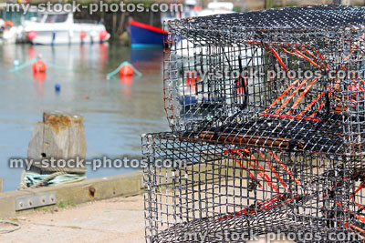 Stock image of rectangular lobster pots at fishing harbour with boats
