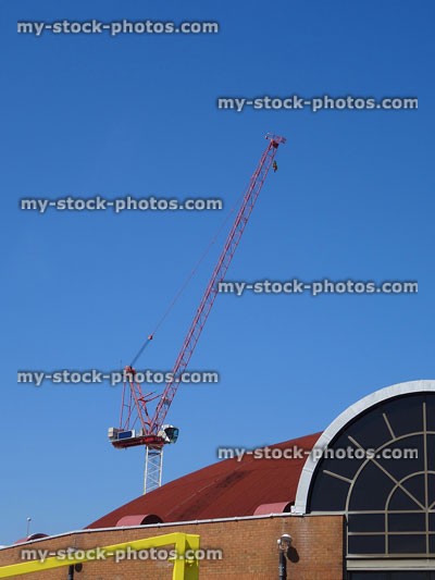 Stock image of red crane on construction site against blue sky