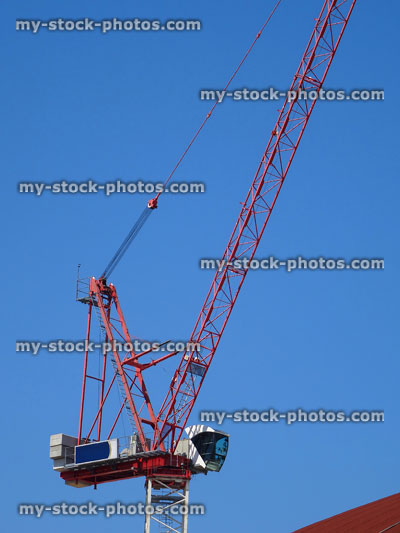 Stock image of red crane working on construction site above buildings