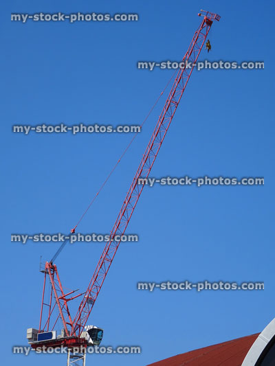 Stock image of red tower crane on building site isolated against blue sky