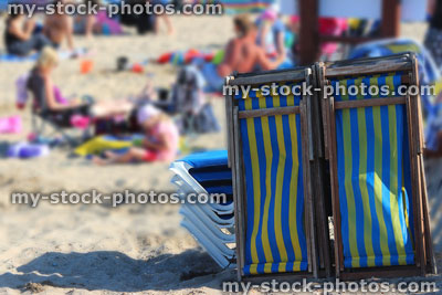 Stock image of stack of striped wooden deckchairs on sandy beach, English seaside