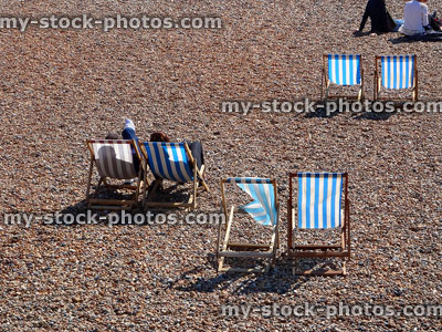Stock image of blue and white canvas deckchairs on pebble beach