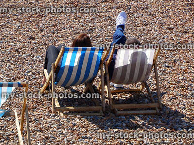 Stock image of holidaymakers sunbathing in deck chairs on pebble beach