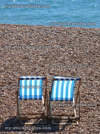 Stock image of two canvas seaside deckchairs on pebble / shingle beach