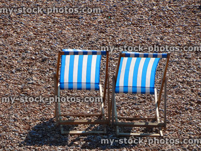 Stock image of blue and white striped deck chairs on pebble beach