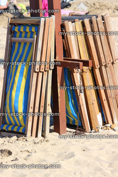 Stock image of stack of striped wooden deckchairs on sandy beach, English seaside