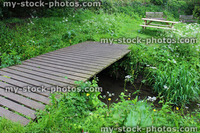Stock image of wooden decking bridge spanning small woodland stream