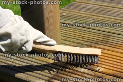 Stock image of cleaning dirty wooden decking by hand, scrubbing with wire brush