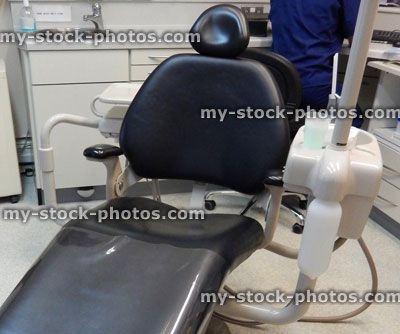Stock image of reclining, black plastic dentist chair in dental surgery