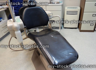 Stock image of reclining, black plastic dentist chair in dental surgery