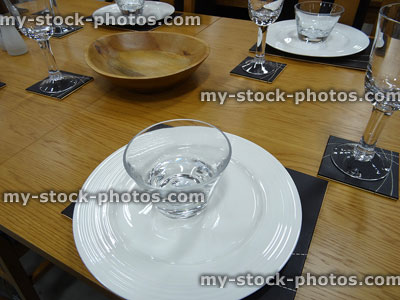 Stock image of dining table set for dinner, white plates, wine glasses, placemats