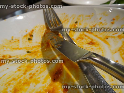 Stock image of dirty plate, remains of meal, knife and fork / cutlery