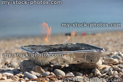 Stock image of flames on disposable barbecue, charcoal bbq on beach