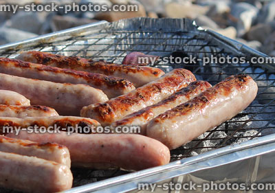 Stock image of browned sausages cooking, barbecue grill, disposable party bbq