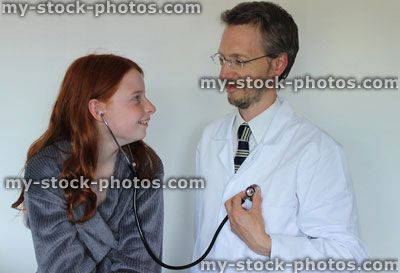 Stock image of young girl in hospital using stethoscope, listening to doctor's heartbeat