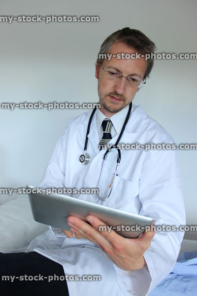 Stock image of young hospital doctor checking results on digital tablet computer screen