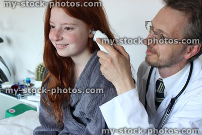 Stock image of hospital doctor taking the temperature of girl with ear thermometer