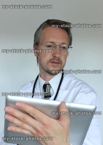 Stock image of young hospital doctor checking results on digital tablet computer screen