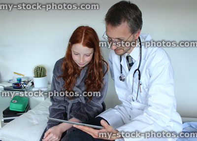 Stock image of hospital doctor showing girl results on tablet computer digital screen