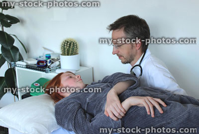 Stock image of sick girl lying down on hospital examination bed with doctor