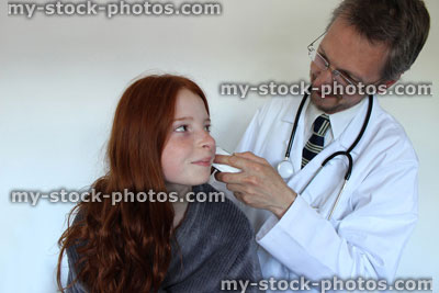 Stock image of hospital doctor taking the temperature of girl with ear thermometer