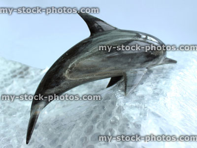 Stock image of marble dolphin ornament surfing on bubblewrap wave