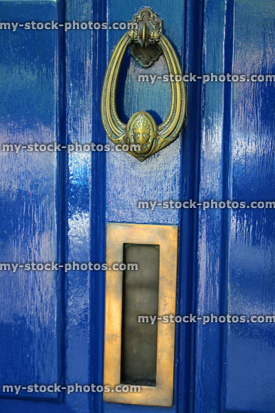 Stock image of ornamental brass door knocker and letterbox on blue front door