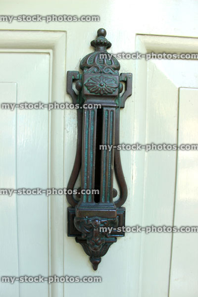 Stock image of ornamental door knocker on pale green front door
