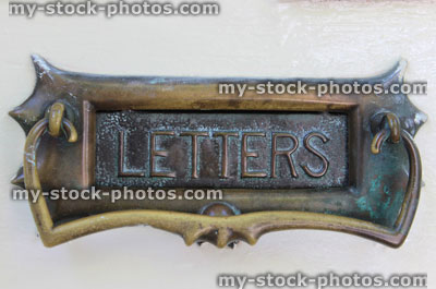 Stock image of ornate brass letter box on white front door