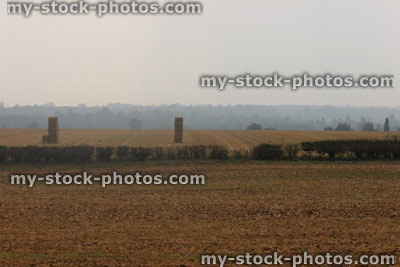 Stock image of early morning hazy countryside view, hedgerow, field, farm